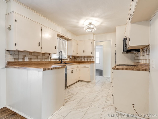 kitchen with a sink, plenty of natural light, tasteful backsplash, light marble finish floors, and ornamental molding