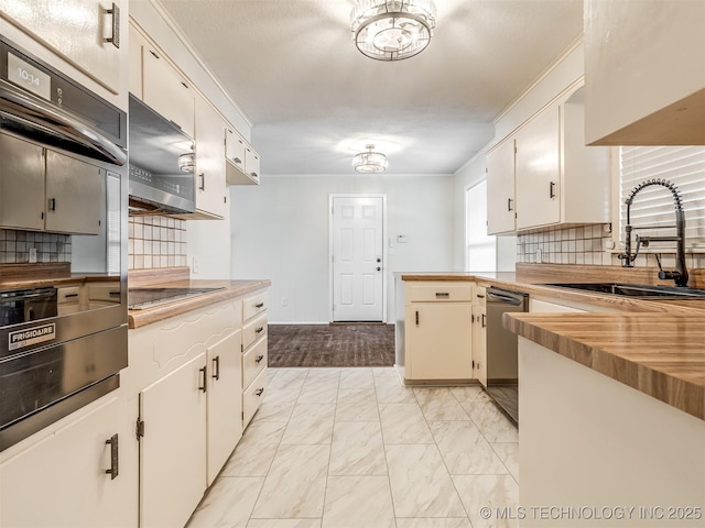 kitchen featuring a sink, appliances with stainless steel finishes, light marble finish flooring, tasteful backsplash, and a peninsula