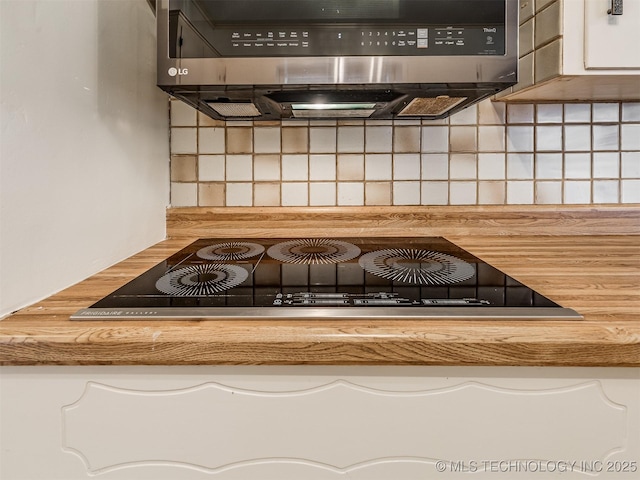 kitchen view of tasteful backsplash, white cabinetry, and black electric cooktop
