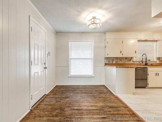 kitchen with dishwasher, a sink, crown molding, tasteful backsplash, and light wood-type flooring
