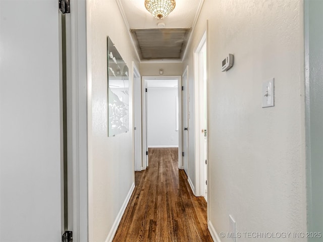 hall featuring attic access, dark wood-style flooring, and baseboards