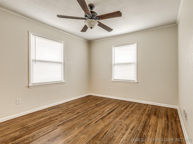 spare room featuring dark wood finished floors, ornamental molding, a ceiling fan, and baseboards
