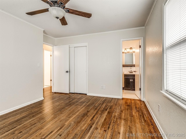 unfurnished bedroom with crown molding, wood finished floors, a sink, a closet, and baseboards
