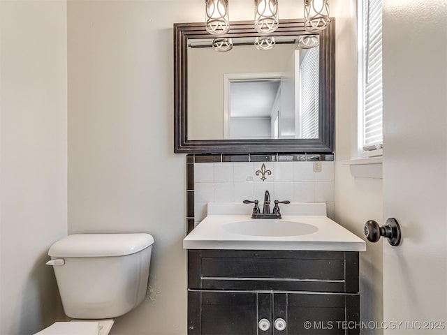 bathroom with decorative backsplash, toilet, and vanity