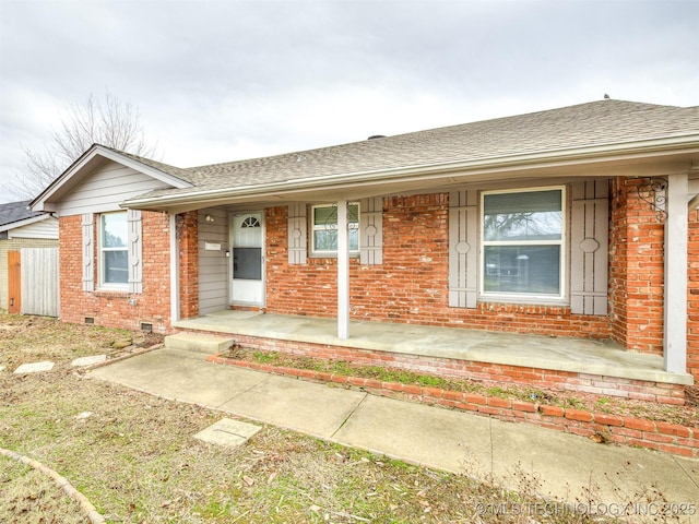 view of front of house with brick siding, covered porch, and roof with shingles