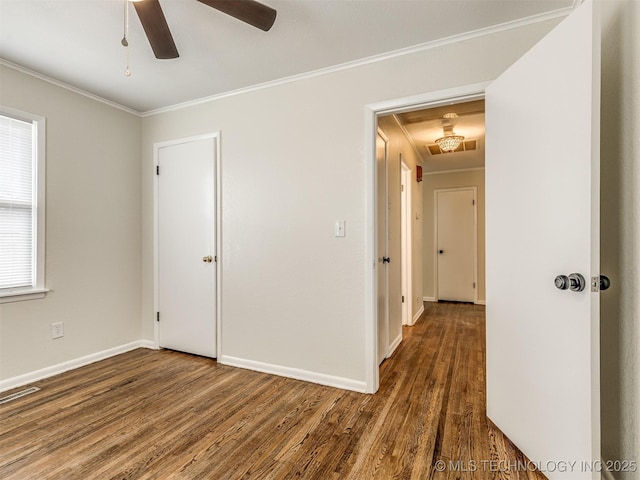 empty room with wood finished floors, crown molding, a ceiling fan, and baseboards