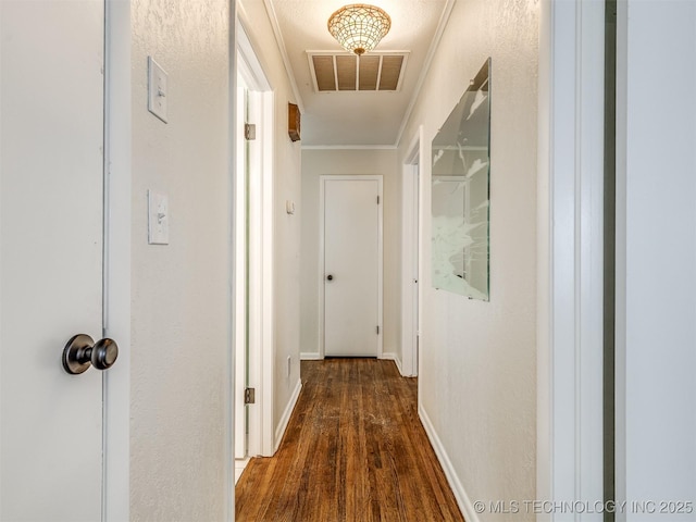 hall featuring wood finished floors, crown molding, and baseboards