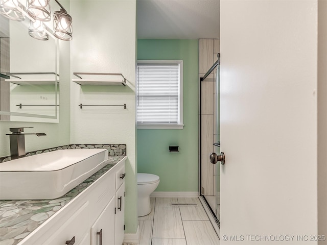 full bathroom with marble look tiles, a stall shower, vanity, toilet, and baseboards