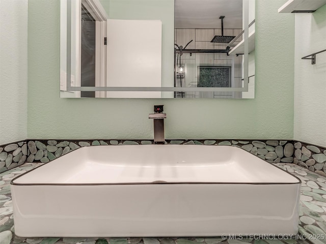 full bath featuring a textured wall and a sink