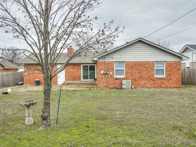 rear view of house with brick siding, central AC, and a chimney