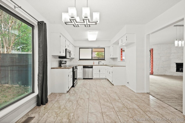 3719 E 84th St, Tulsa, OK 74137 - kitchen with stainless steel appliances, a sink, a chandelier, white cabinets, and light colored carpet