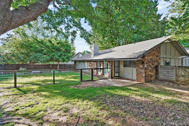 3719 E 84th St, Tulsa, OK 74137 - rear view of house featuring stone siding, a chimney, board and batten siding, and a shingled roof