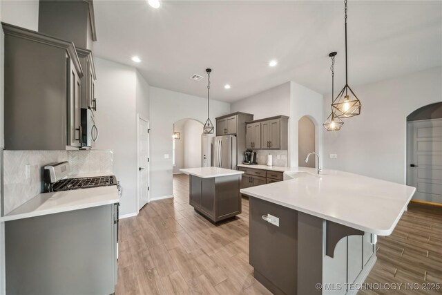 11807 N 131st E Ave, Owasso, OK 74055 - kitchen featuring appliances with stainless steel finishes, arched walkways, a sink, gray cabinets, and decorative backsplash
