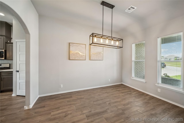 11807 N 131st E Ave, Owasso, OK 74055 - unfurnished dining area featuring arched walkways, dark wood finished floors, baseboards, and lofted ceiling