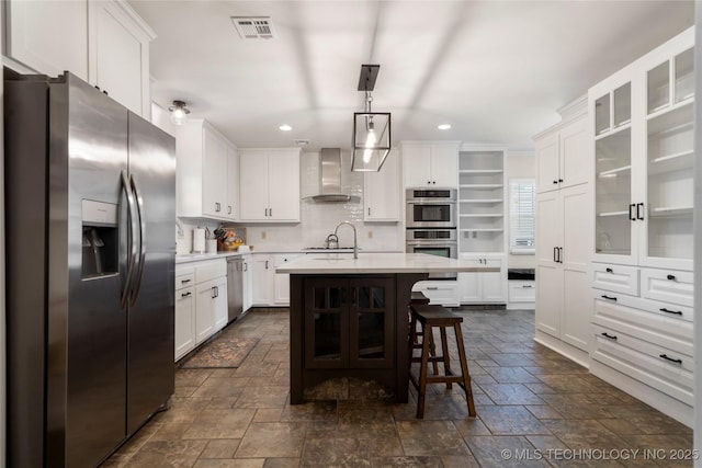 kitchen featuring stainless steel appliances, stone tile floors, wall chimney range hood, recessed lighting, and light countertops