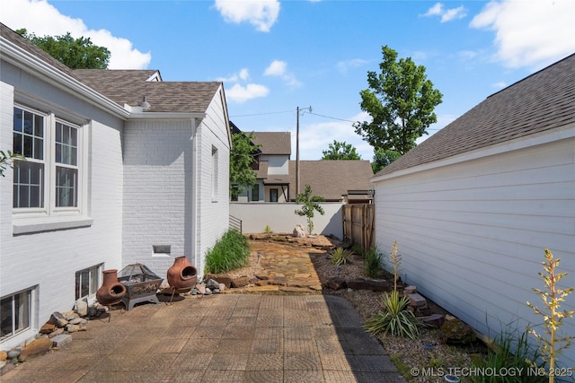 2303 S Delaware Pl, Tulsa, OK 74114 - view of side of home with brick siding, fence, a patio, and a shingled roof