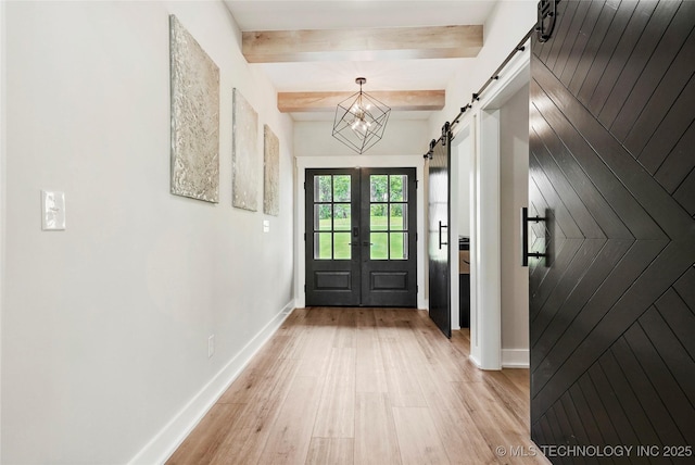 doorway featuring a barn door, light wood-style flooring, beamed ceiling, baseboards, and french doors
