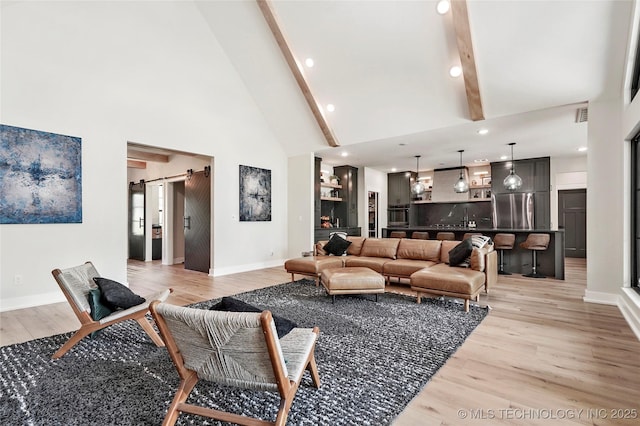 living room featuring a barn door, high vaulted ceiling, light wood-style floors, beamed ceiling, and baseboards