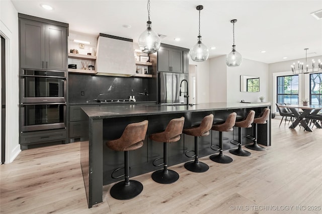 kitchen with appliances with stainless steel finishes, open shelves, light wood finished floors, recessed lighting, and a sink