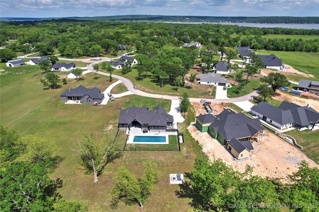 aerial view of property's location featuring a pool, nearby suburban area, and a forest