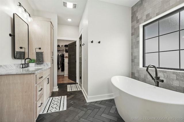 bathroom with a spacious closet, baseboards, vanity, a soaking tub, and a shower stall