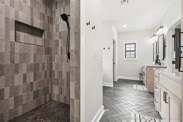 full bath featuring baseboards, tiled shower, vanity, and recessed lighting