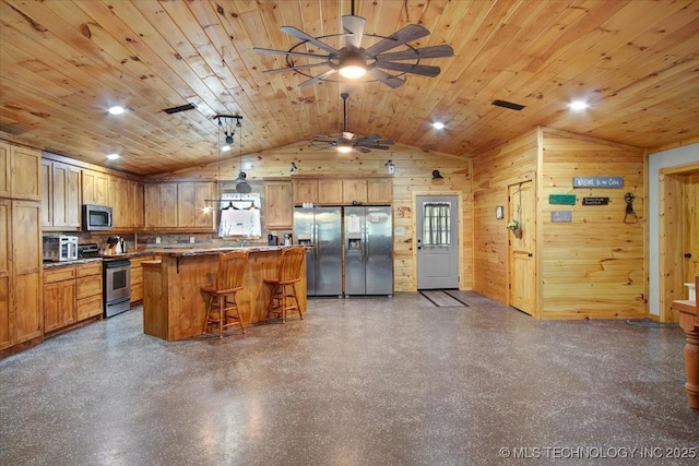 10627 Old Willis, Kingston, OK 73439 - kitchen featuring stainless steel appliances, lofted ceiling, a kitchen breakfast bar, wooden walls, and ceiling fan