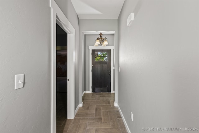 corridor with baseboards and a chandelier