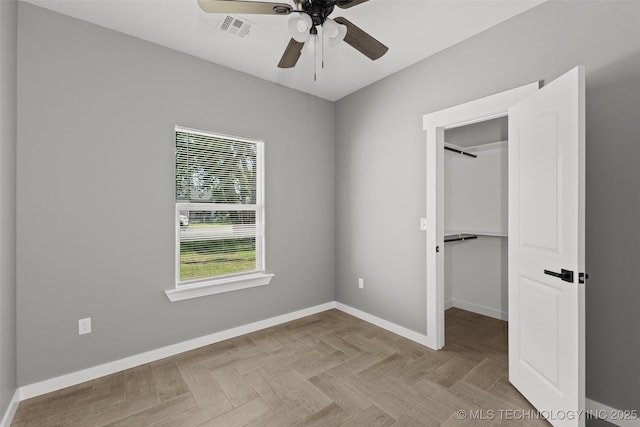 unfurnished bedroom with baseboards, a spacious closet, ceiling fan, and a closet