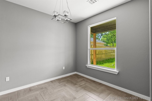 unfurnished room featuring baseboards and a chandelier