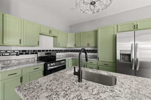 kitchen featuring stainless steel appliances, green cabinetry, a sink, a chandelier, and light stone counters