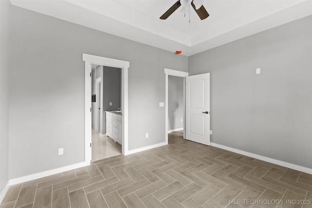 unfurnished bedroom with baseboards, ensuite bath, and a ceiling fan
