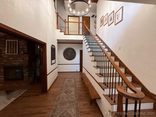 15373 N Javine Hill Rd, Skiatook, OK 74070 - stairway with wood finished floors, a towering ceiling, a chandelier, and a fireplace