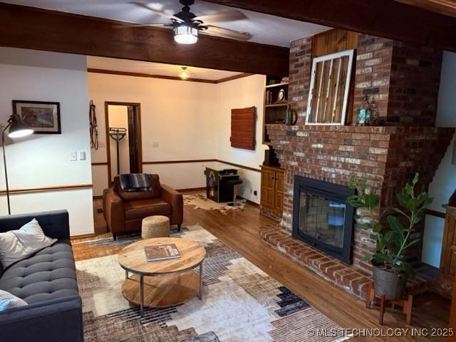 15373 N Javine Hill Rd, Skiatook, OK 74070 - living area with wood finished floors, beamed ceiling, a ceiling fan, and a fireplace