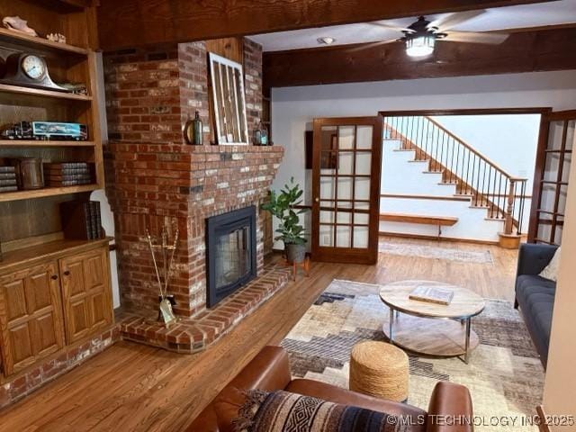 15373 N Javine Hill Rd, Skiatook, OK 74070 - living area featuring wood finished floors, a ceiling fan, a fireplace, beam ceiling, and french doors