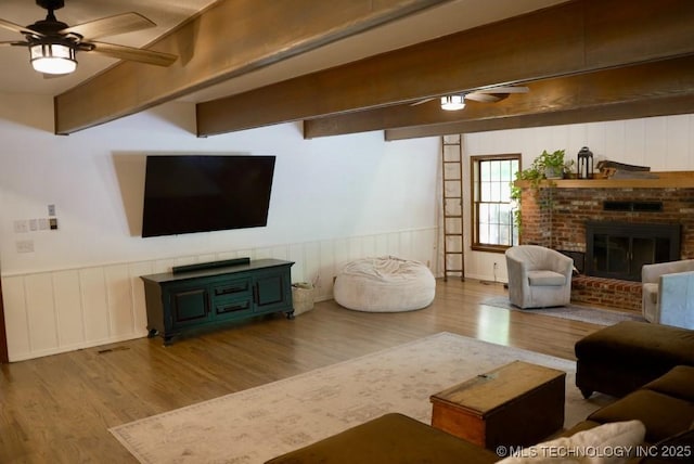 15373 N Javine Hill Rd, Skiatook, OK 74070 - living area featuring wood finished floors, ceiling fan, a fireplace, and a wainscoted wall