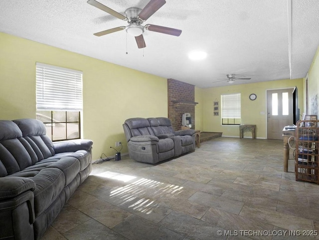 311 Washington Ave, Boswell, OK 74727 - living room with a ceiling fan, stone tile flooring, a textured ceiling, baseboards, and a brick fireplace