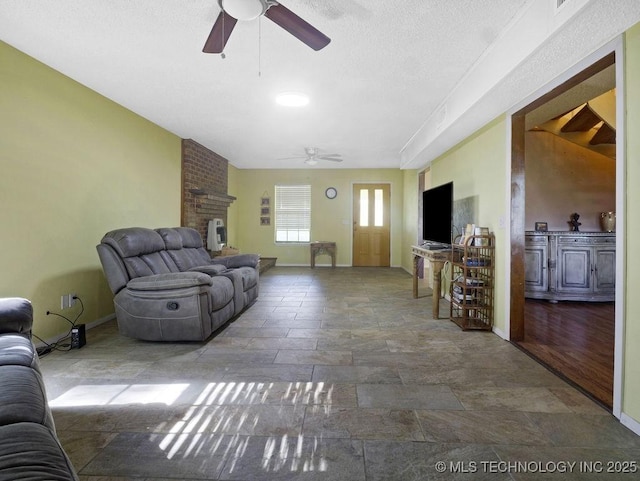 311 Washington Ave, Boswell, OK 74727 - living room with a ceiling fan, stone finish flooring, baseboards, a fireplace, and a textured ceiling