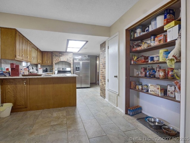 311 Washington Ave, Boswell, OK 74727 - kitchen featuring appliances with stainless steel finishes, a peninsula, a textured ceiling, open shelves, and brown cabinets