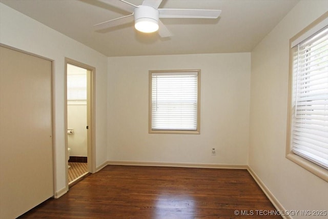 6112 E 21st St, Tulsa, OK 74114 - unfurnished bedroom with multiple windows, dark wood finished floors, and baseboards