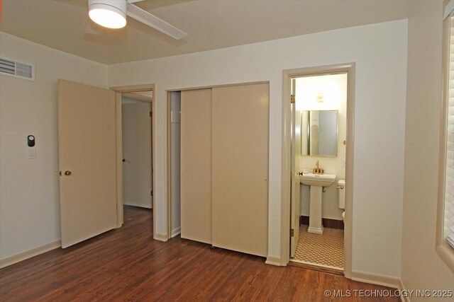 6112 E 21st St, Tulsa, OK 74114 - unfurnished bedroom with dark wood-type flooring, a closet, ensuite bathroom, baseboards, and a sink