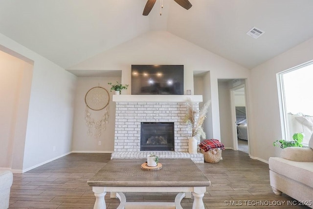 living area featuring a ceiling fan, wood finished floors, lofted ceiling, a fireplace, and baseboards