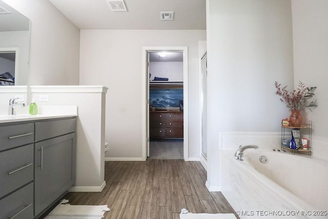 full bath featuring a stall shower, wood finished floors, a walk in closet, vanity, and a bath