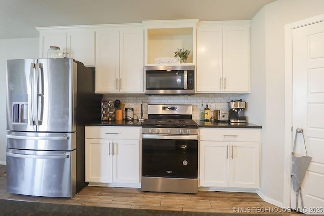 kitchen with appliances with stainless steel finishes, tasteful backsplash, dark wood finished floors, and white cabinets