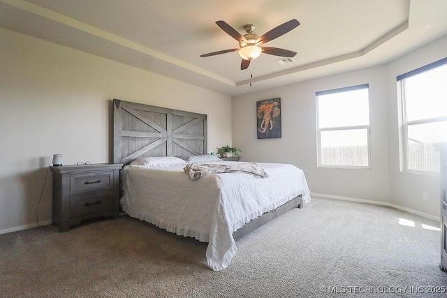 bedroom with a raised ceiling, baseboards, and carpet flooring