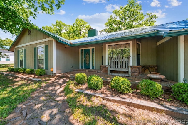 1005 N Rigsby Rd, Cleveland, OK 74020 - back of house featuring a chimney, covered porch, and metal roof