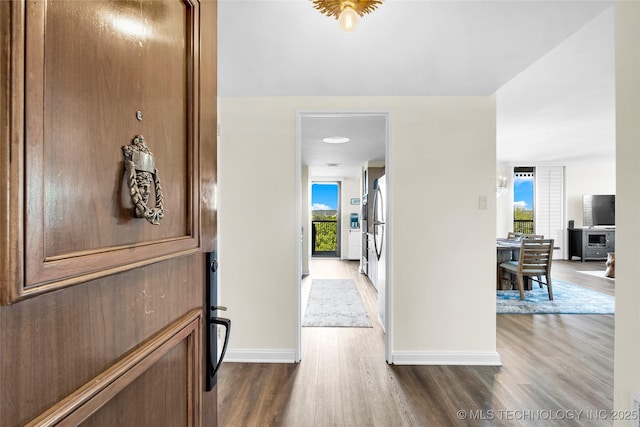 corridor featuring dark wood-style flooring and baseboards