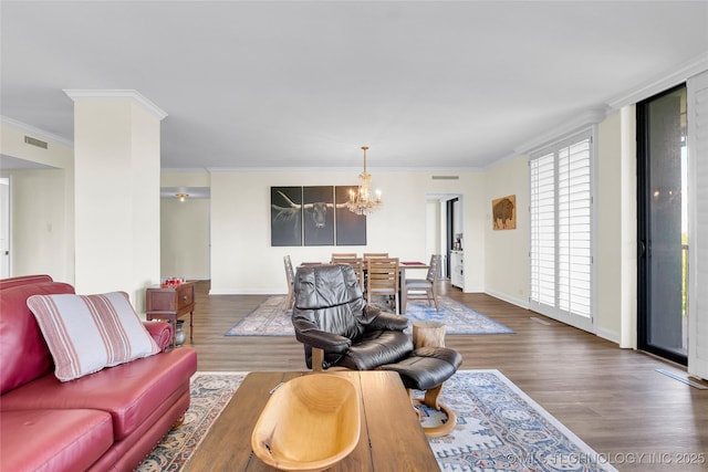 living room featuring ornamental molding, a chandelier, wood finished floors, and baseboards