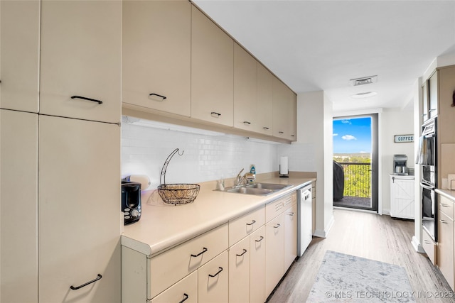 kitchen featuring a sink, white dishwasher, tasteful backsplash, light countertops, and light wood-type flooring