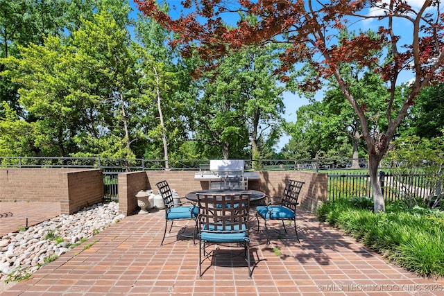 view of patio / terrace featuring fence, outdoor dining area, and view of scattered trees